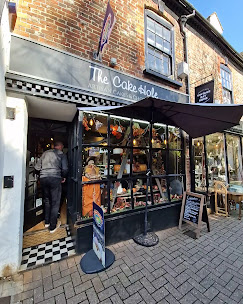 The Cake Hole shopfront with its striped awning and window display on Churchyard in Hitchin